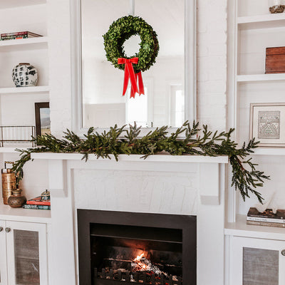 Preserved christmas Wreath with red ribbon on mirror and mantle
